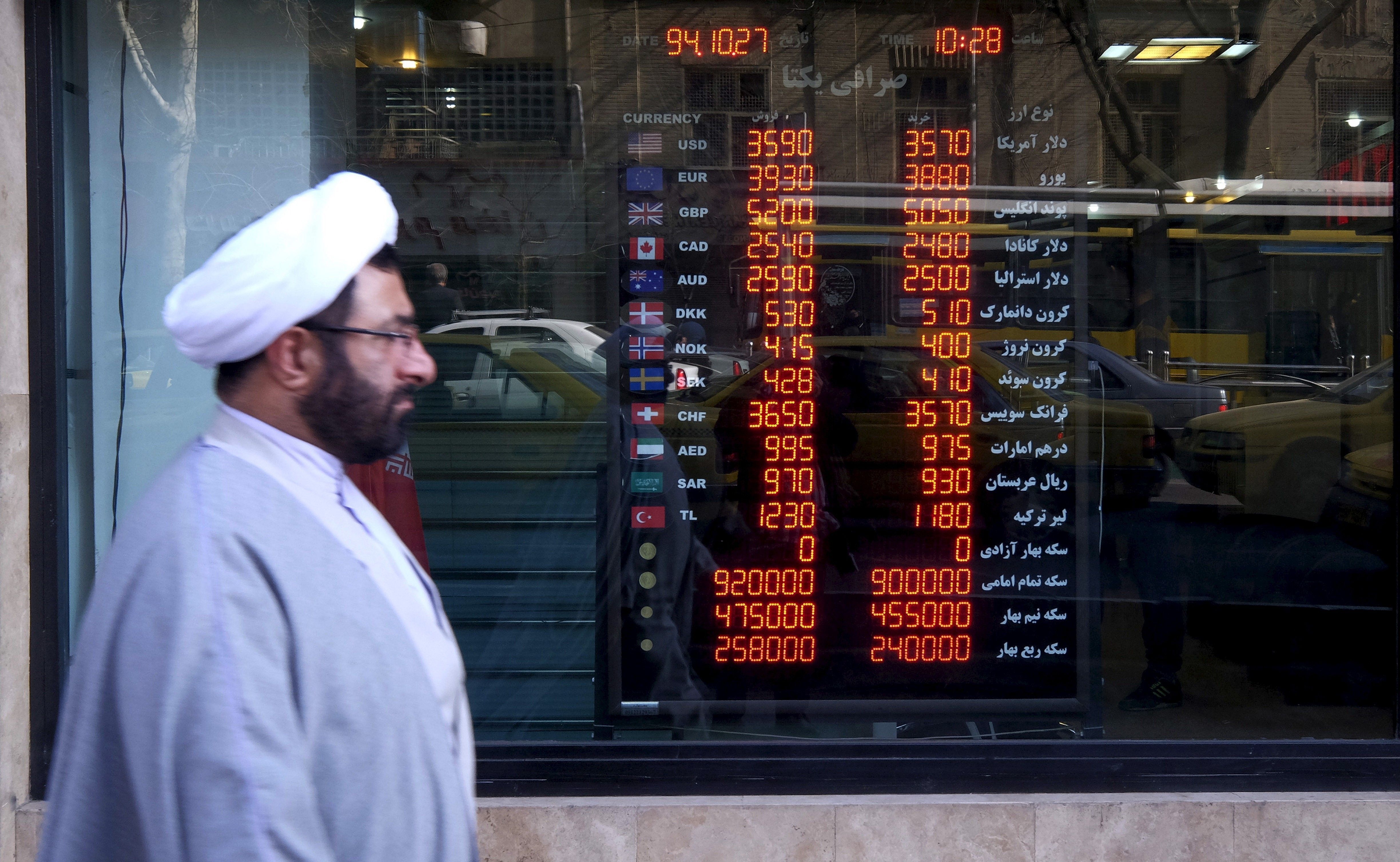 FILE PHOTO: A cleric walks past a currency exchange shop in Tehran's business district, Iran. REUTERS/Raheb Homavandi/TIMAATTENTION EDITORS - THIS IMAGE WAS PROVIDED BY A THIRD PARTY. FOR EDITORIAL USE ONLY.