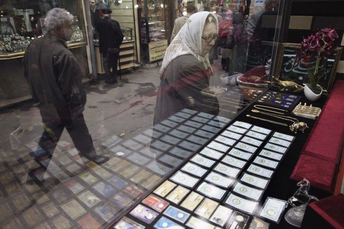 A woman looks at gold coins at a shop window in a bazaar in northern Tehran