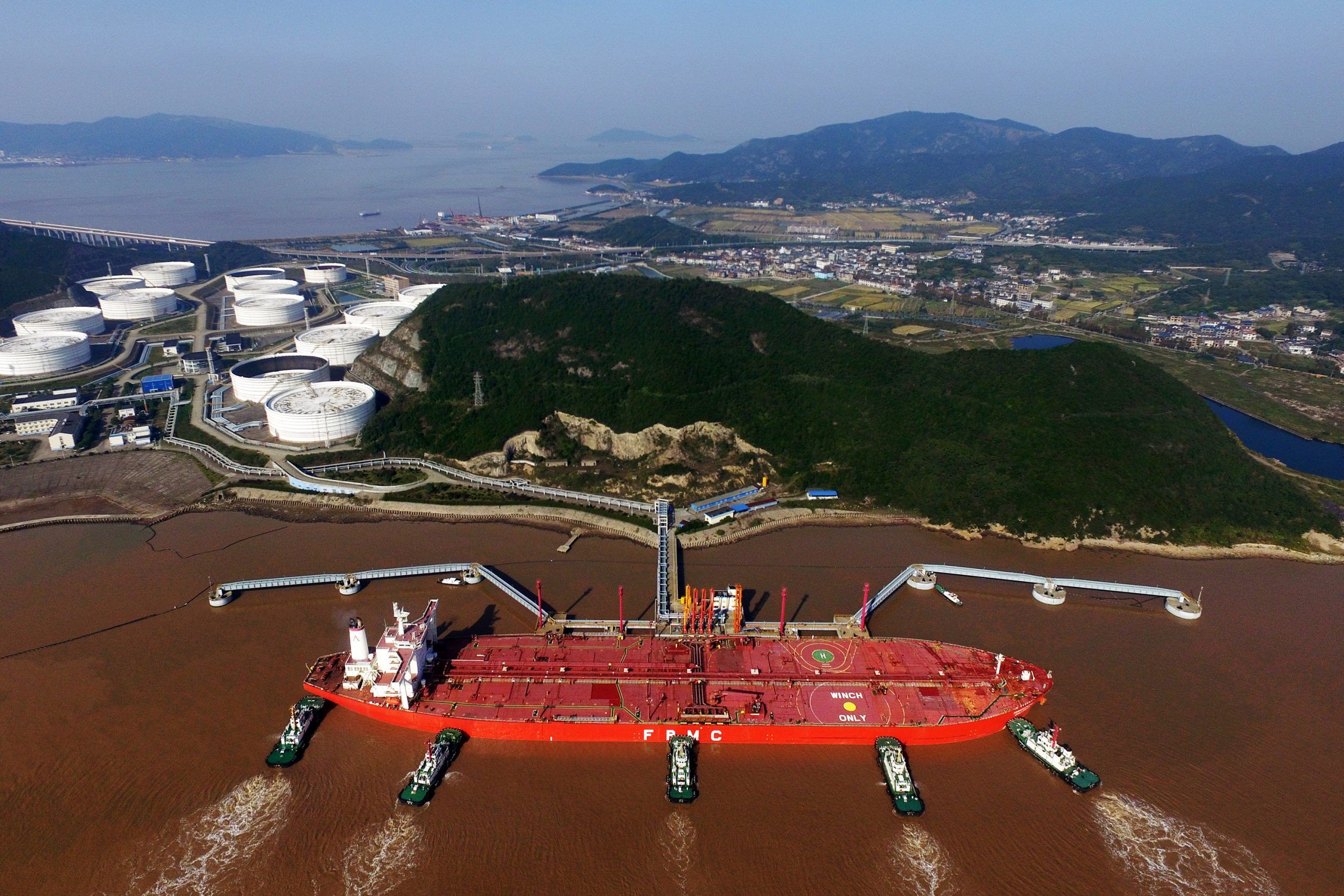 FILE PHOTO: Tugboats dock an oil tanker on a crude oil quay at the Port of Zhoushan in Zhoushan city, east China's Zhejiang.