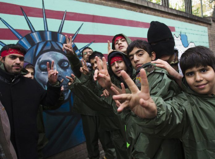 Members of the Basij militia flash victory signs in front of an anti-U.S. mural to mark Basij week in Tehran