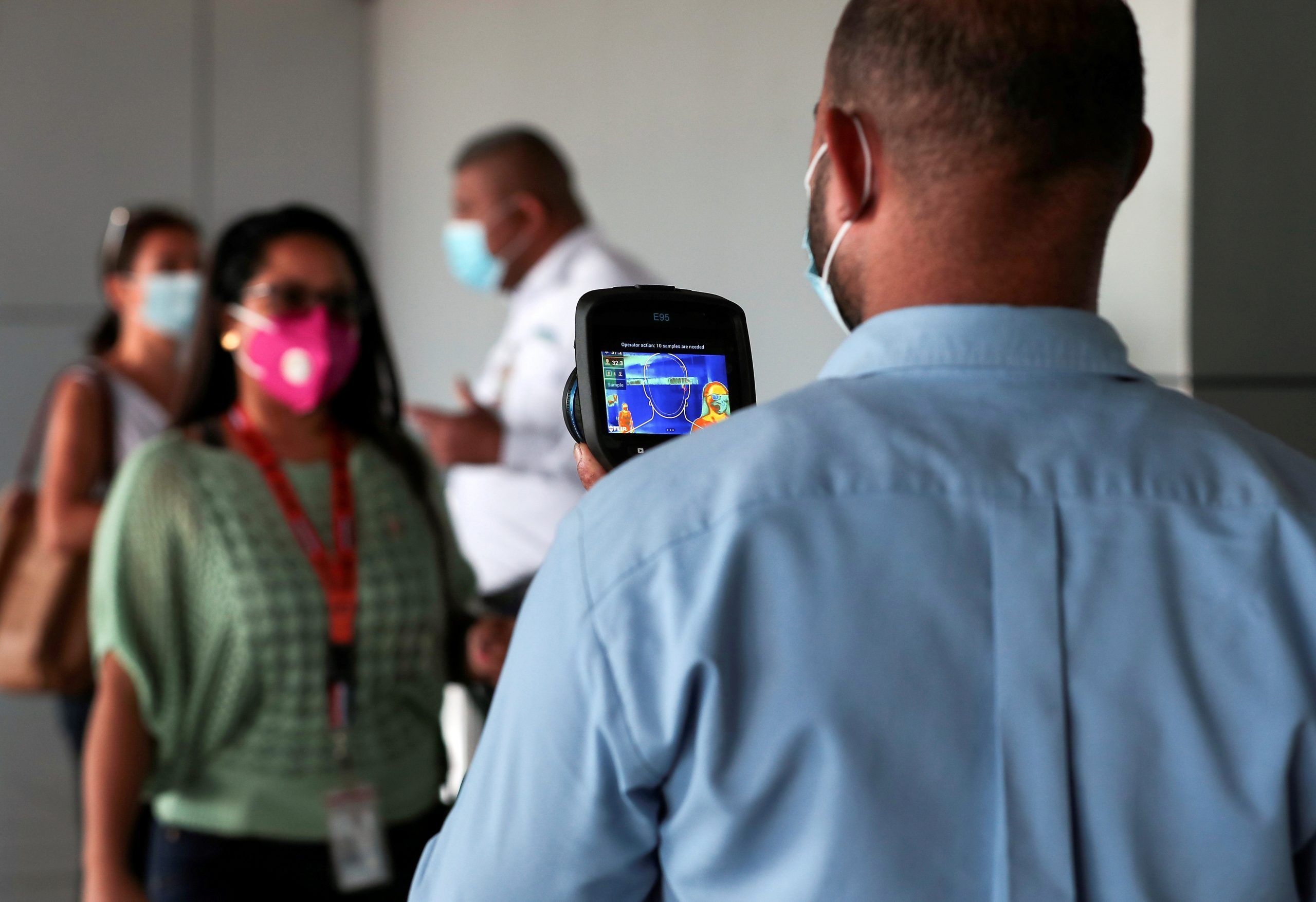 FILE PHOTO: An employee measures the temperatures of travelers at the Tocumen International Airport during the coronavirus disease (COVID-19) outbreak, in Panama City, Panama October 16, 2020. Picture taken October 16, 2020. REUTERS/Erick Marciscano/File Photo
