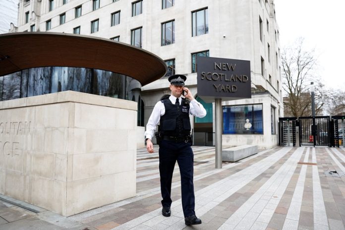 FILE PHOTO: A police officer walks outside New Scotland Yard, the headquarters of the Metropolitan Police, in London
