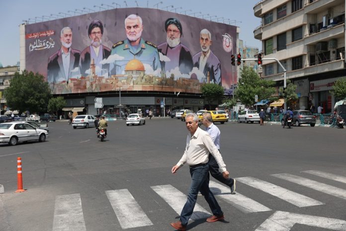 Iranians walk next to a billboard in Tehran