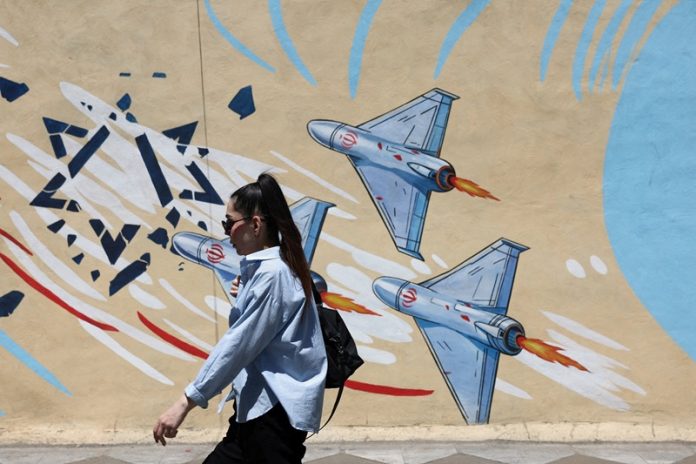 An Iranian woman walks next to an anti-Israeli mural on a street in Tehran
