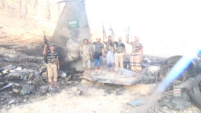 Houthi fighters stand in front of what they say is a downed Saudi jet, at a location given as Yemen