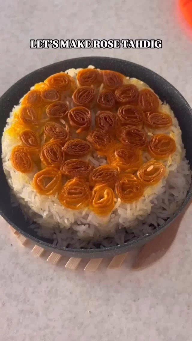 Lavash Bread Rose Tahdig
May 24, 2025 - Video and recipe by TahdigLover on social media.

This Lavash Bread Rose Tahdig is a stunning fusion of taste and artistry, where crispy layers of lavash are elegantly rolled into delicate rose shapes. The golden crust and intricate design make it a show-stopping centerpiece that is as visually captivating as it is delicious.

Ingredients:
– 2-3 sheets of lavash bread
– 2 cups basmati rice, washed and soaked
– 2-3 tablespoons plain yogurt
– 2-3 tablespoons saffron water (prepared by steeping a pinch of saffron in hot water)
– 3-4 tablespoons melted butter or oil
– Salt (to taste)

Steps:

1. Prepare the Base: Boil the basmati rice until it’s just shy of fully cooked, then drain.
2. Cut and Roll Lavash: Cut the lavash bread into long strips. Roll each strip into a rose-like shape by curling the edges inward.
3. Layer the Tahdig: In a large, non-stick pot, mix yogurt, saffron water, a pinch of salt, and 1-2 tablespoons of melted butter. Spread this mixture evenly at the base.
4. Place the Roses: Arrange the rolled lavash roses on top of the saffron-yogurt mixture in a circular pattern.
5. Add the Rice: Gently layer the par-cooked rice over the lavash roses, being careful not to disrupt them. Drizzle the remaining melted butter or oil over the top.
6. Cook Slowly: Cover the lid with a clean kitchen towel to catch condensation and place it securely on the pot. Cook on low heat for about 30-40 minutes, until the rice is steamed and the lavash bottom forms a golden, crispy crust.
7. Unveil and Serve: Once ready, carefully flip the pot onto a large serving plate to reveal the tahdig and your beautiful lavash rose creation!
.
#kayhanlife #persianfood #kayhanlifefoodbloggers #lavash #tahdig